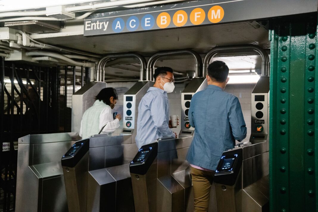 Pasajeros cruzan los torniquetes de una entrada del metro de Nueva York con lectores de pago sin contacto