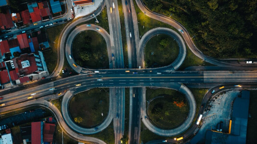 Vista aérea de un intercambiador vial en forma de trébol en Ciudad de Panamá al anochecer, con tráfico en movimiento