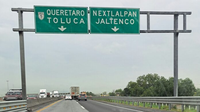 Paro de Canacar sigue: 38 puntos el lunes y una mesa sin ella Tractocamiones y autos circulan por el Circuito Exterior Mexiquense bajo un letrero hacia Querétaro y Toluca