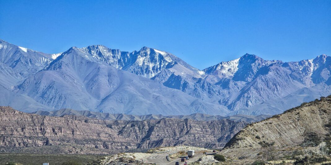 Camión en una ruta de montaña con la cordillera de los Andes al fondo