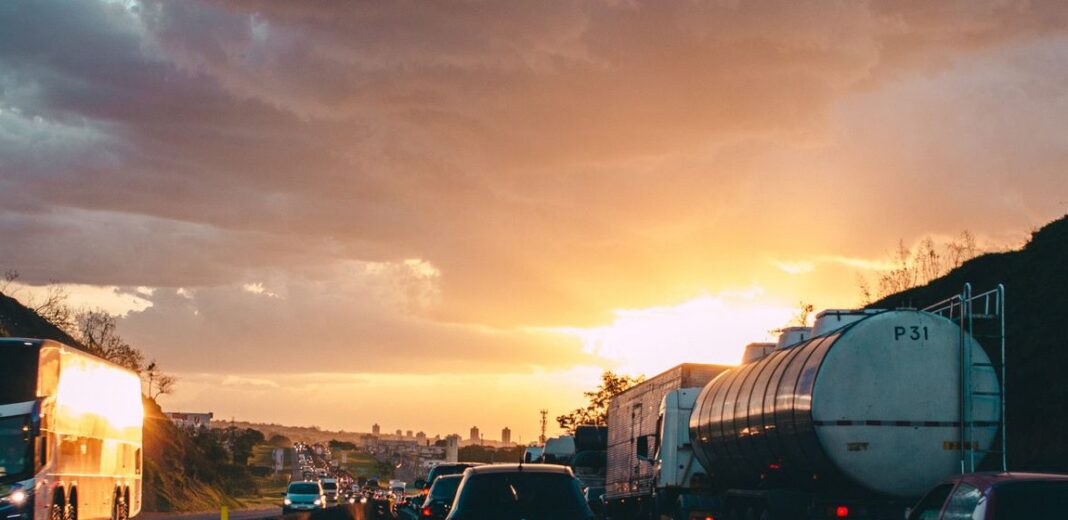 Autotanque detenido entre autos y camiones en una carretera congestionada al atardecer