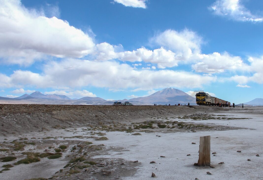 Tren de carga cruza el altiplano boliviano con montañas al fondo