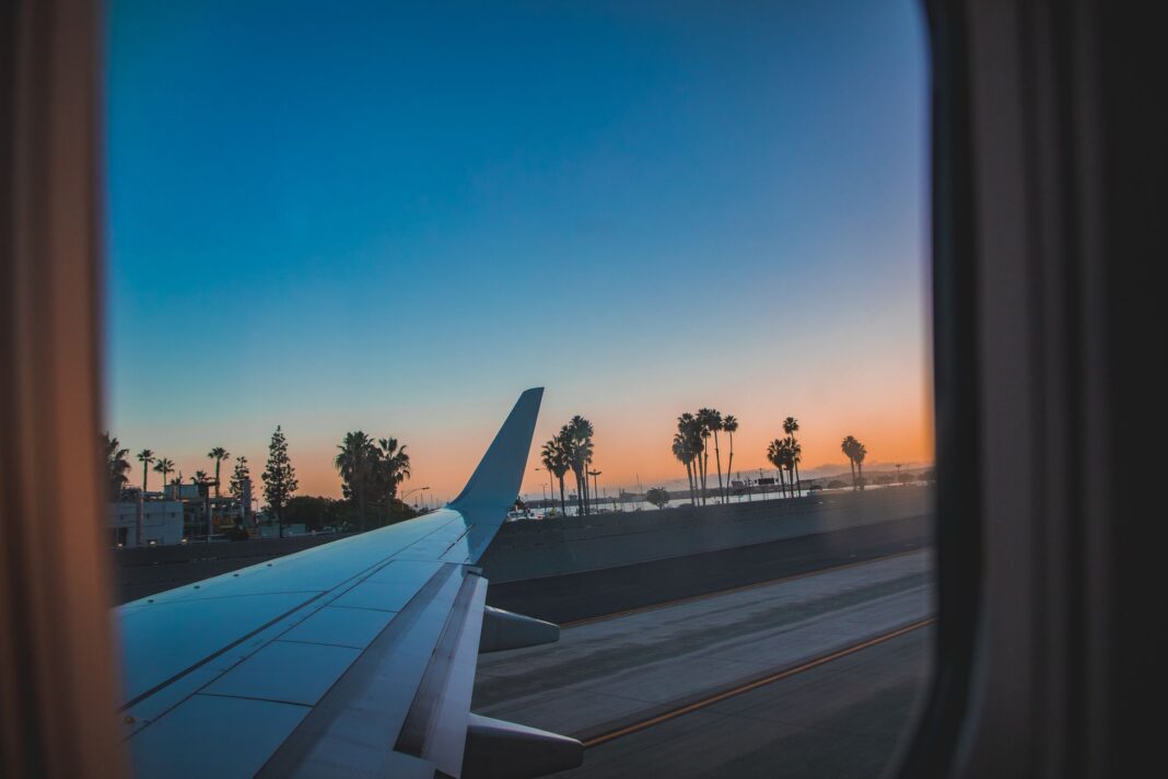 Montería estrena vuelo a Panamá con Satena: 150 sillas por semana Ala de un avión comercial en pista al atardecer, con palmeras al fondo