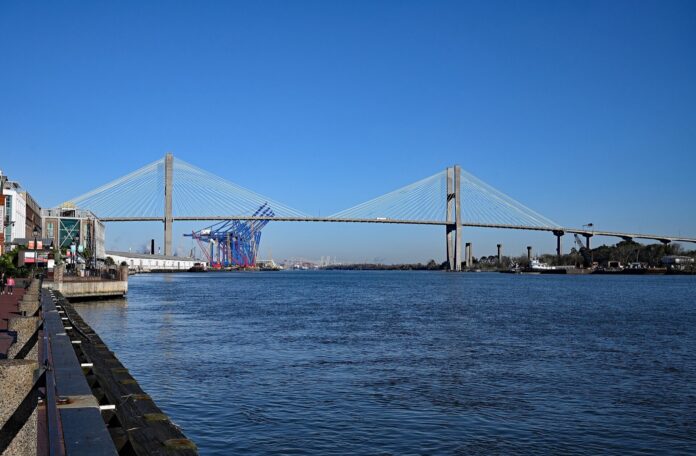 Puerto de Savannah logra permiso para terminal de 3,5 M de TEU Río Savannah con el puente Talmadge al fondo y grúas de contenedores en la orilla, visto desde el malecón de River Street