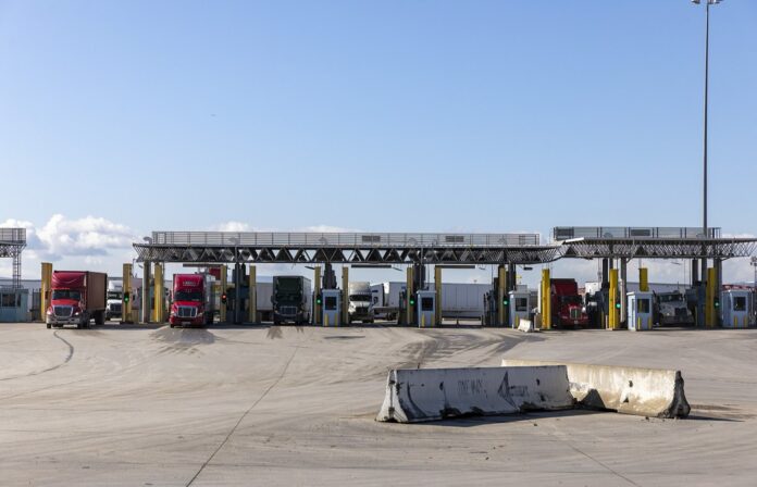 Tijuana: abre el libramiento Otay I-Otay II para camiones vacíos Tractocamiones avanzan hacia las casetas de inspección de carga de la garita de Otay Mesa, con semáforos en verde bajo las techumbres metálicas