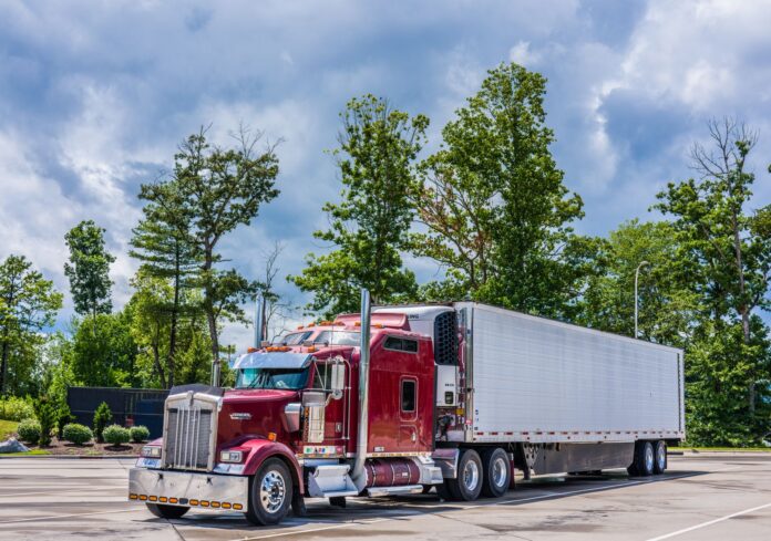 México exporta 144% más vehículos pesados y vende 11% menos Tractocamión rojo con caja refrigerada estacionado en un patio de concreto