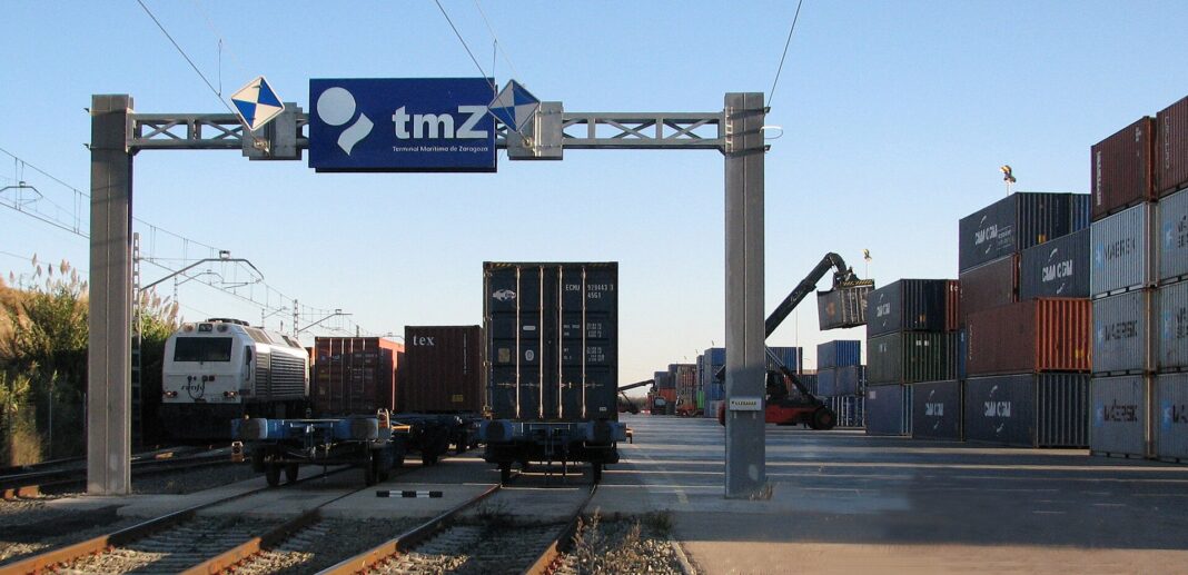 Pórtico de la Terminal Marítima de Zaragoza con un tren portacontenedores y contenedores apilados